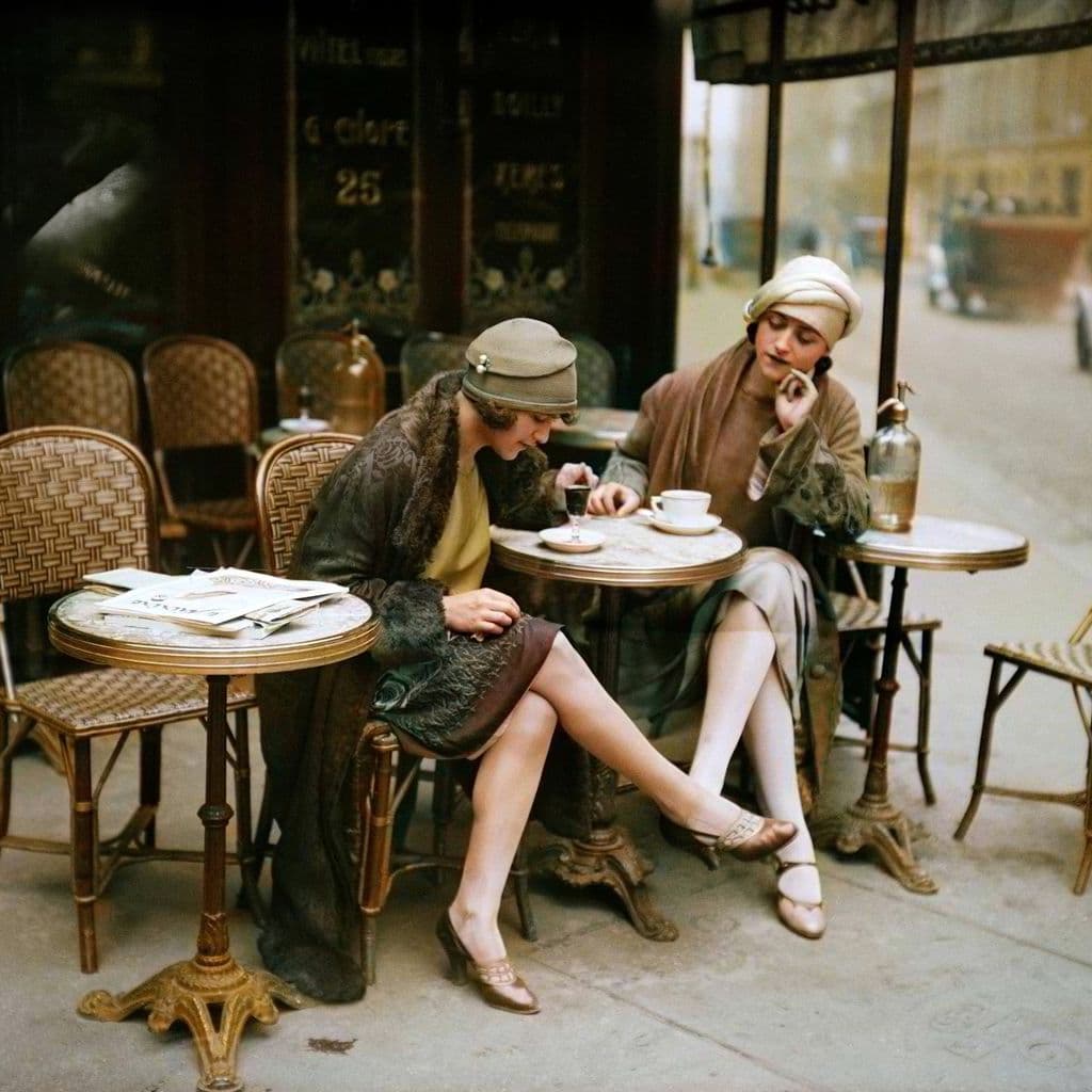 Two women in mid twentieth century dress sit at a cafe