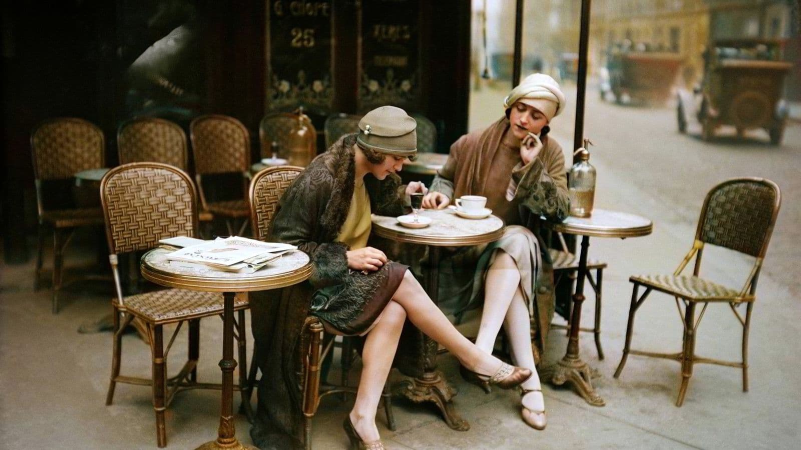Two women in mid twentieth century dress sit at a cafe